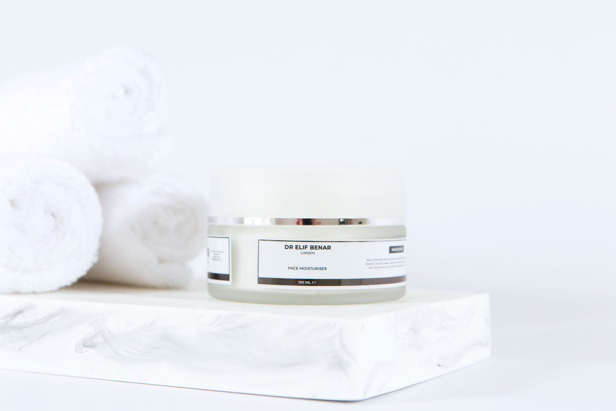 Dr Elif Benar Face Moisturiser jar on white marble with rolled white towels