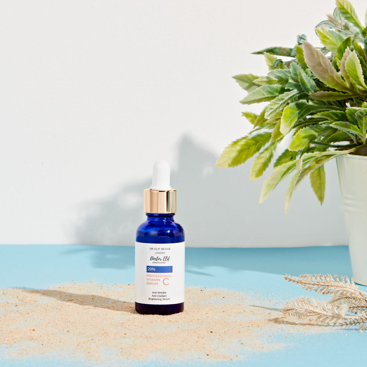 Dr Elif Benar Professional Vitamin C Serum on sand with a green plant and summer sunlight